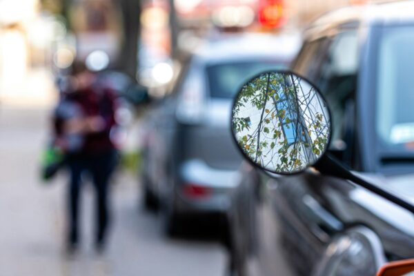 close-up of a motorcycle mirror parked on the side of the street, soft focus, blurred background